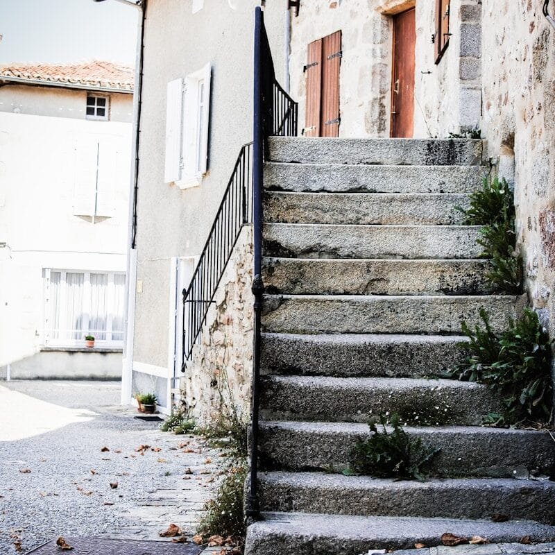 gray concrete stairs between white concrete building during daytime